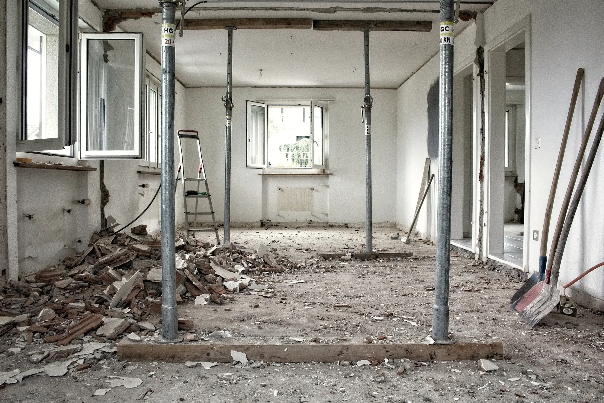 An interior during renovation, with exposed wall edges, support posts, and rubble